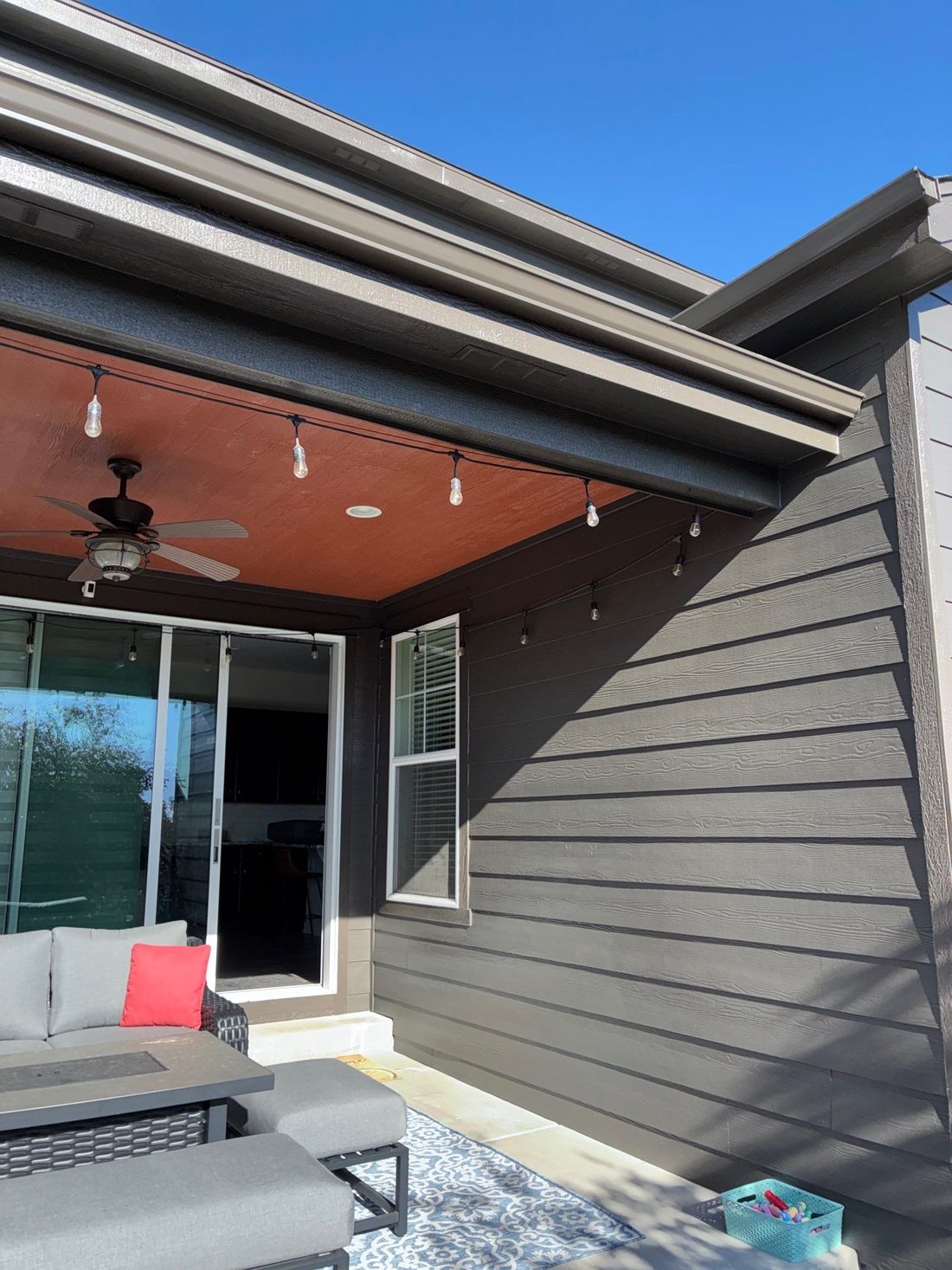 Covered patio with a burnt-orange ceiling and charcoal lap siding on a Castle Rock home
