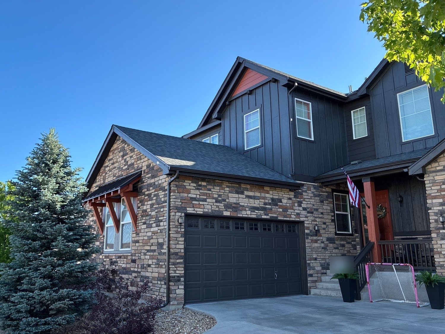 Exterior color combo in Castle Rock: charcoal board-and-batten body with burnt-orange gable, corbels, and porch posts