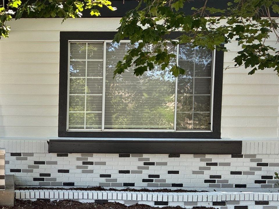 Whitewashed brick wainscot below a dark-trimmed window on a warm white Castle Rock exterior