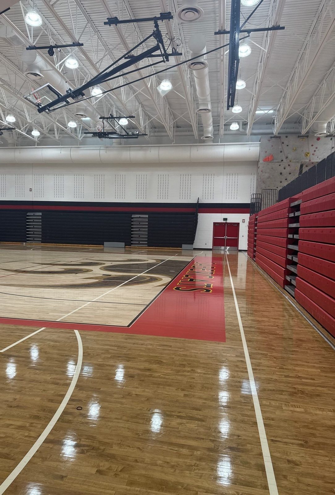 Repainted Castle View High School main gym in Castle Rock, CO, with bright white walls and black and red banding above the bleachers