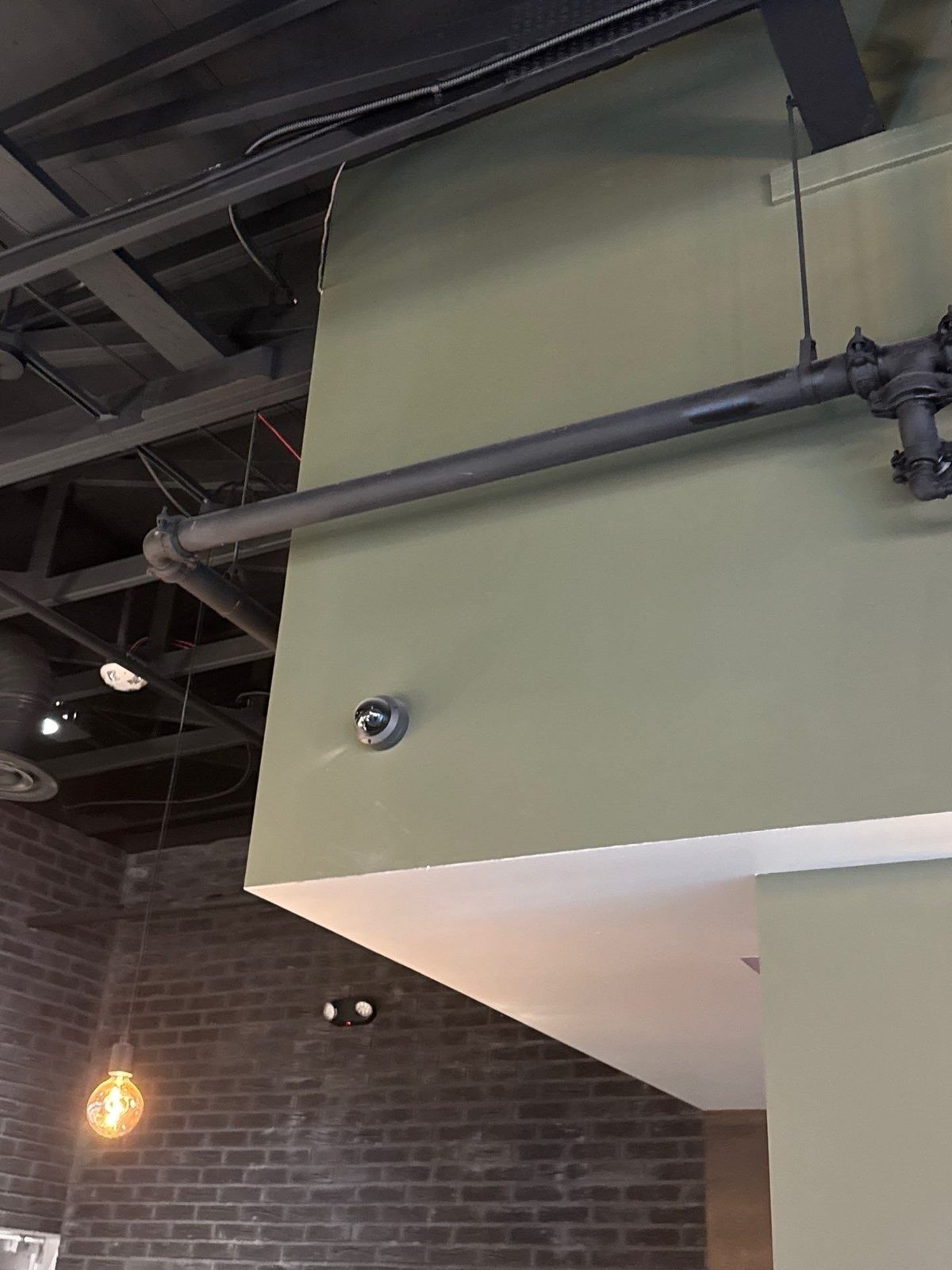 Sage accent wall with painted exposed pipe at Scileppi's restaurant in Castle Rock